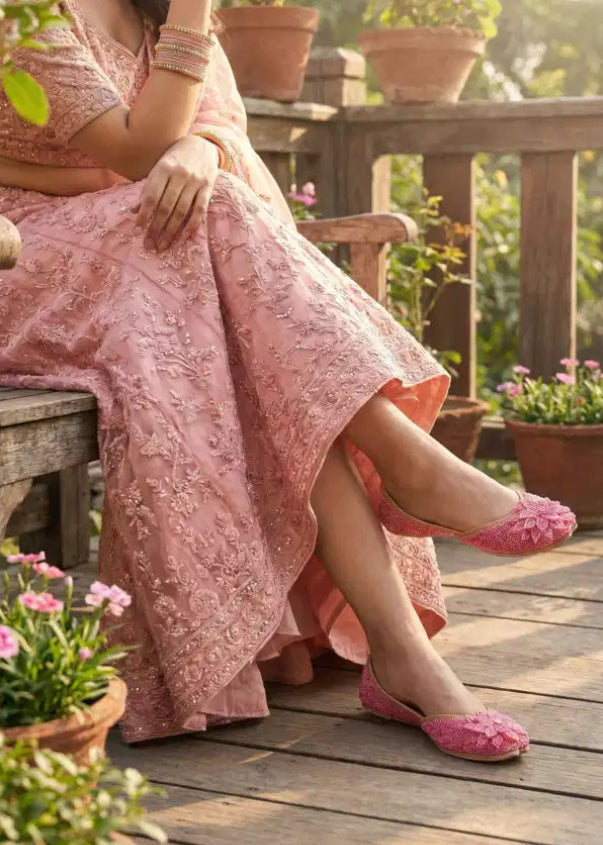 Woman in a pink traditional outfit sitting on a wooden deck with potted plants around.